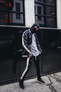 man wears gray shirt and black zip jacket standing near black metal cabinet thumbnail