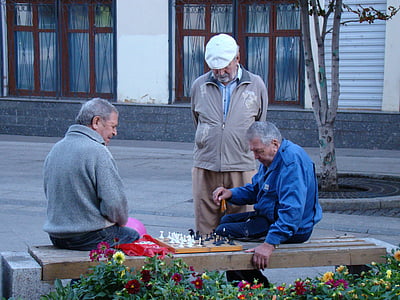 man looking on two men playing chess thumbnail