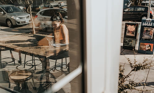 woman sitting on brown wooden chair in front of glass wall thumbnail