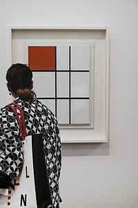woman looking at white and brown abstract painting thumbnail