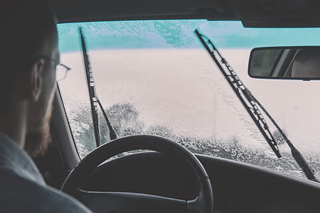 man driving car during rainy day with wipers wiping water thumbnail
