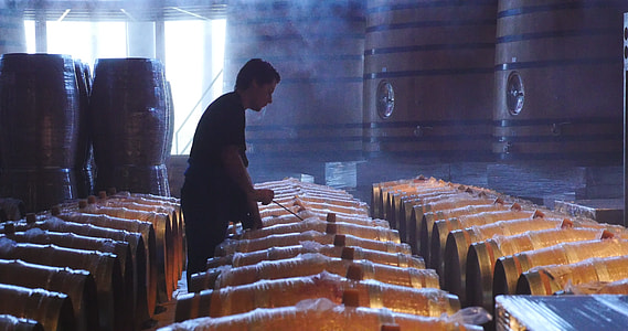 man standing beside wooden barrels thumbnail