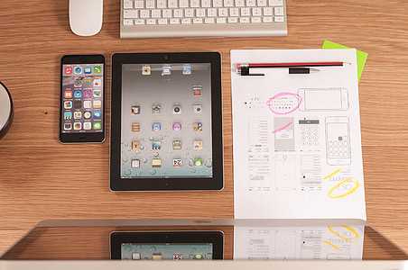 black iPad beside iPhone on brown wooden table thumbnail