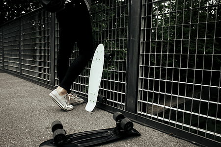 person standing near railings with white and black cruiser boards thumbnail