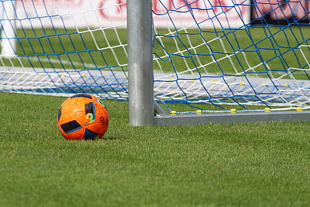 orange and black soccer ball beside soccer goal on soccer field thumbnail