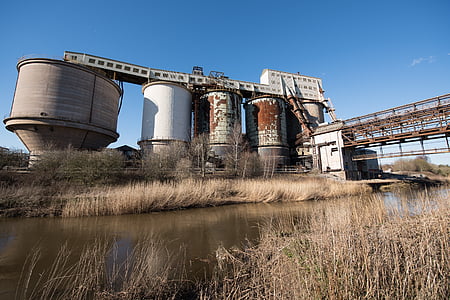gray and white metal tanks near body of water thumbnail