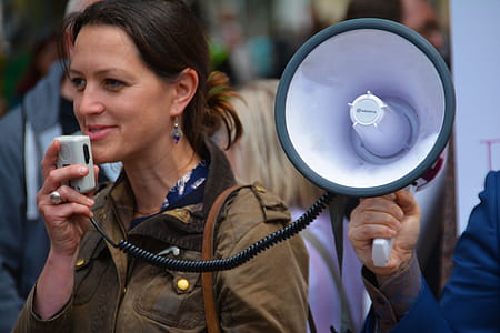 woman in brown jacket holding megaphone during daytime thumbnail