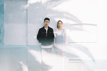 man and woman near white wall at daytime thumbnail