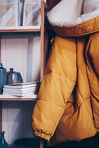 orange parka jacket hanging beside shelf thumbnail