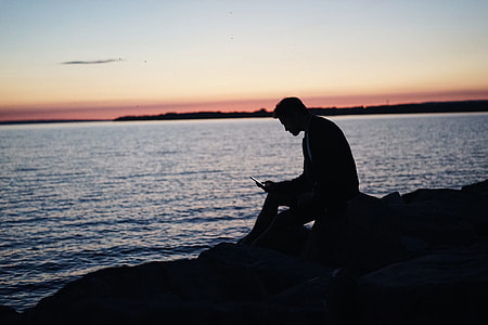 silhouette of man sitting near sea thumbnail