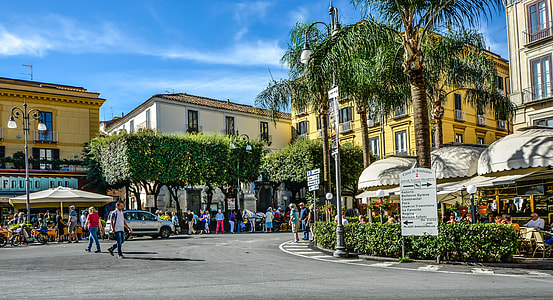 people walking besides yellow and white building during daytime thumbnail