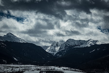 white and black mountains under cloudy sky thumbnail