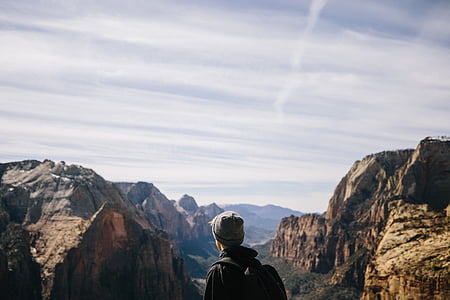 man wearing backpack facing rock formations thumbnail