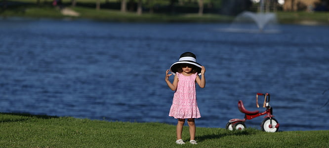 man standing on grass field in front of calm water at daytime thumbnail