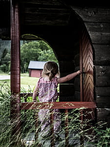 baby standing beside wooden door during daytime thumbnail