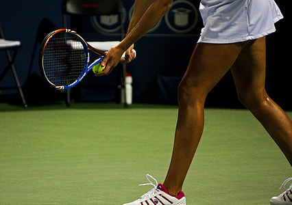 woman wearing white skirt and pair of white sneakers holding tennis racket thumbnail