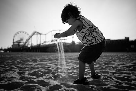 boy playing sand overlooking ferris wheel greyscale photography thumbnail