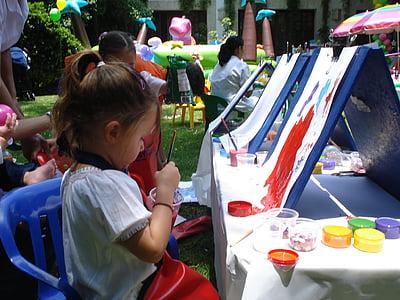 girl holding paintbrush sitting in front of painting thumbnail