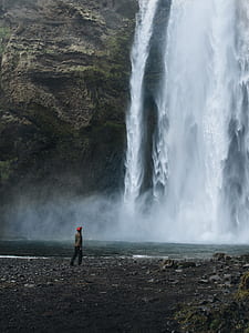 person standing near waterfalls thumbnail