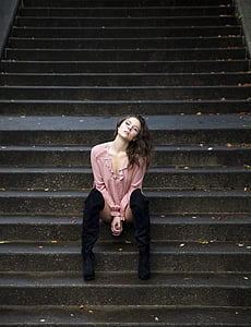 woman wearing pink long-sleeved shirt sitting on black concrete stairs thumbnail