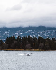 white and black plane ascending on water under cloudy sky thumbnail