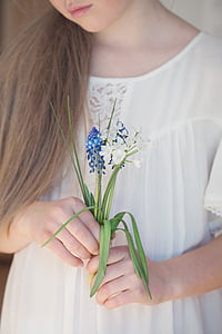 woman in white holding blue and white flowers thumbnail