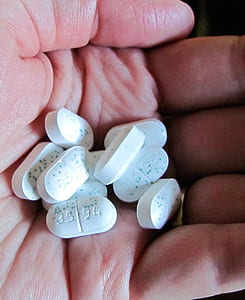 person holding white medication pills thumbnail