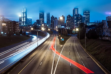 timelapse photography of red and white lights crossing on road with building ahead during nighttime thumbnail