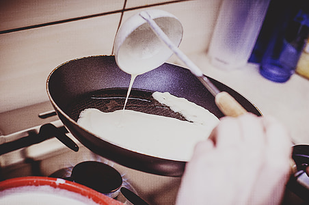 person holding pouring white cream using ladle on frying pan on stove thumbnail