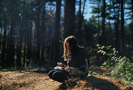 woman in black and grey sweater near trees at daytime thumbnail