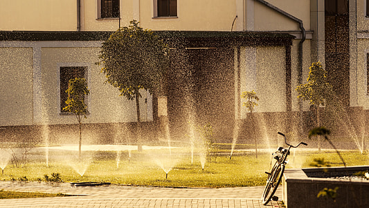 bike leaning on concrete rails with turned-on garden sprinklers thumbnail