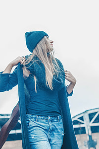 woman in black knit hat with black scarf and shirt with blue denim bottoms standing outside during daytime thumbnail