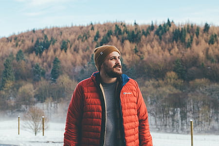 man wearing orange coat with a view of trees thumbnail