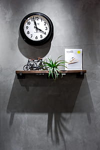 round black and white analog wall clock near brown wooden floating shelf thumbnail