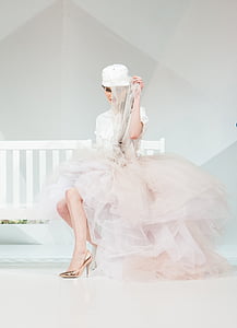 woman in white and pink dress sits on white wooden bench thumbnail