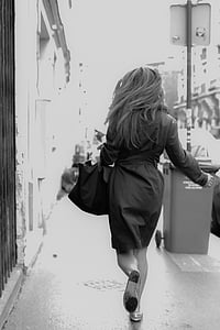 greyscale photography of woman walking on sidewalk thumbnail