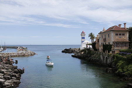 white boat in water near lighthouse thumbnail
