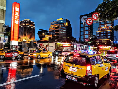 assorted-color vehicles in the middle of road surrounded with buildings thumbnail