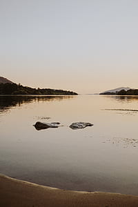 rocks on body of water surrounded with mountain thumbnail