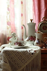 white-green-and-red ceramic tea set on brown table and white crochet tablecloth thumbnail