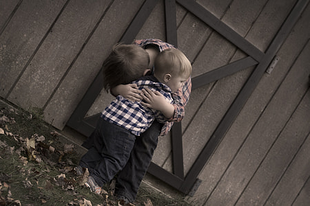 boy in orange checked dress shirt hugging boy in white and blue checked dress shirt during daytime thumbnail