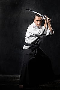 man holding gray katana near black wall thumbnail