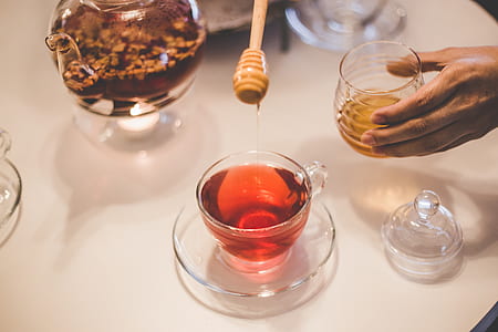 person holding clear glass container with honey thumbnail