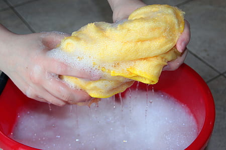 person washing yellow shirt on red plastic basin thumbnail