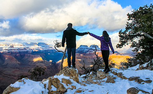 man and woman holding hands standing on top of cliff thumbnail