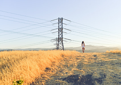 person standing on grass field near electricity post thumbnail