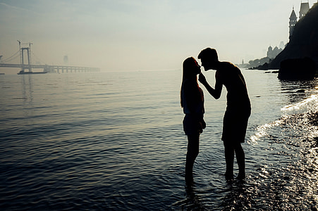 silhouette of woman and man standing on sea shore thumbnail