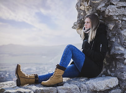 Woman in Black Coat Sitting on Rock thumbnail
