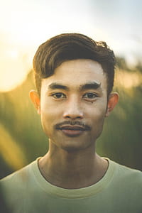 close up photography of man wearing yellow crew-neck shirt looking straight thumbnail