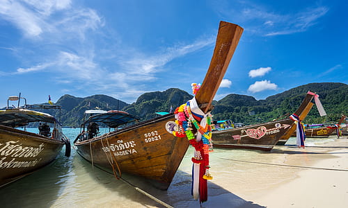 boats on seashore near mountain thumbnail